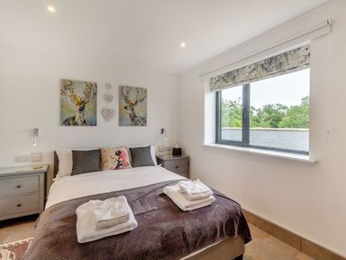 A bedroom with a bed and towels on it two bedside tables and a window at Secret Kingdom Cottage in Warkworth