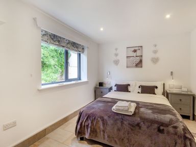 A bedroom with a double bed between two nightstands under a window at Secret Kingdom Cottage in Warkworth