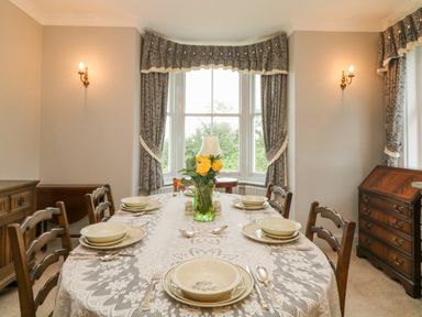 A dining room with a table set for six with dishes and a vase of yellow flowers at Silver Crooks Trewyn Nr Holsworthy