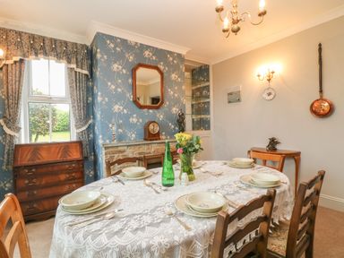 A dining room with a table set for six and floral wallpaper at Silver Crooks in Trewyn Nr Holsworthy