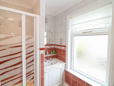 A bathroom with a shower cubicle a sink with cabinet and a frosted window at Silver Crooks in Trewyn Nr Holsworthy