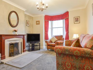 A living room with patterned armchairs and sofa a fireplace and a television at Silver Crooks in Trewyn Nr Holsworthy