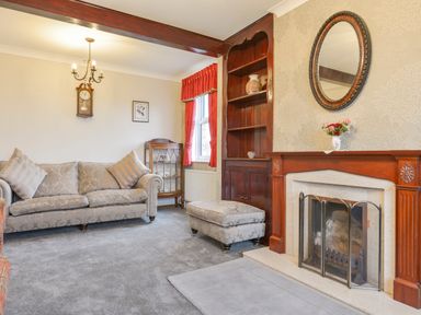 A living room with a sofa an ottoman and a fireplace at Silver Crooks in Trewyn Nr Holsworthy