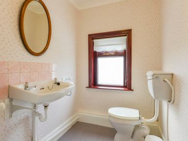 A bathroom with a wall-mounted sink and a toilet with a high level cistern and a window with a roller blind at Silver Crooks in Trewyn Nr Holsworthy
