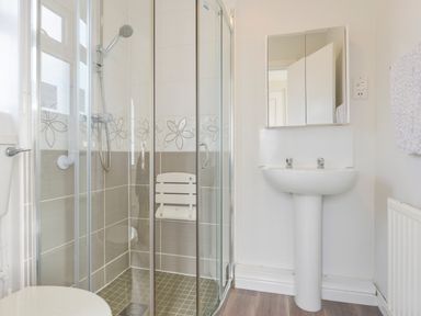 A bathroom with a glass shower enclosure a white pedestal sink a toilet and a towel on the wall at Silver Crooks Trewyn Nr Holsworthy