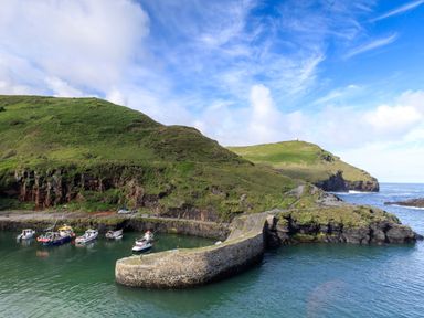 A small harbor with boats docked next to a stone pier and green hills in the background at Silver Crooks Trewyn Nr Holsworthy