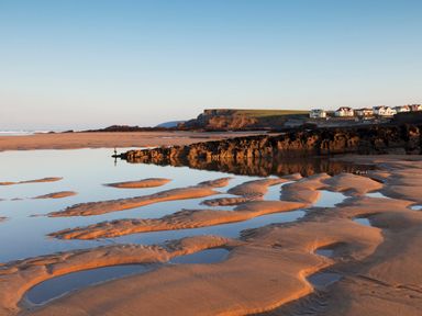 A sandy beach with tidal pools and rocks near houses on a cliff at Silver Crooks in Trewyn Nr Holsworthy
