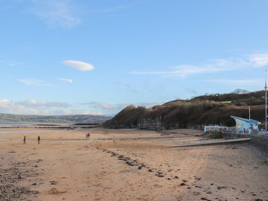 A beach with sand people walking and hills in the background at 4 Parc Delfryn Brynteg near Benllech