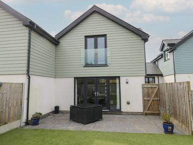A backyard with a paved patio area furniture and potted plants at 4 Parc Delfryn Brynteg near Benllech