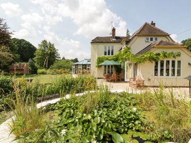 A garden pond with water lilies in front of a house with patio furniture at Valley House in Devizes