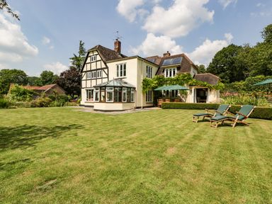 A large house with a well-kept lawn outdoor seating and sun loungers at Valley House in Devizes