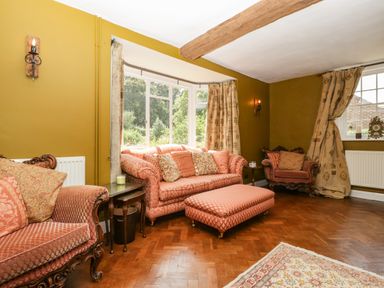 A living room with sofas armchairs ottoman and windows at Valley House in Devizes