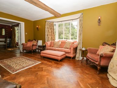 A living room with patterned sofas an ottoman and a rug and wooden floor at Valley House in Devizes