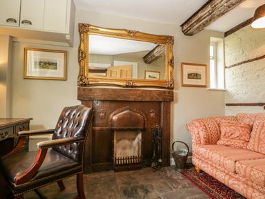 A sitting room with a leather armchair a patterned sofa a fireplace with a large ornate mirror above at Valley House in Devizes