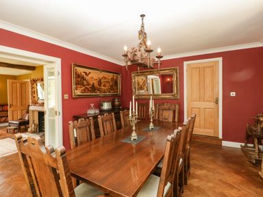 A dining room with a wooden table and chairs a chandelier and paintings at Valley House in Devizes