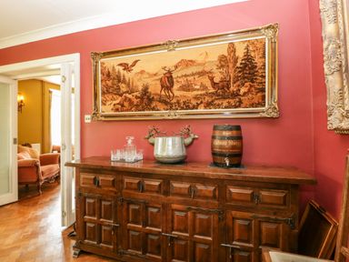 A wooden sideboard with glassware and a barrel under a framed nature tapestry in a room at Valley House in Devizes