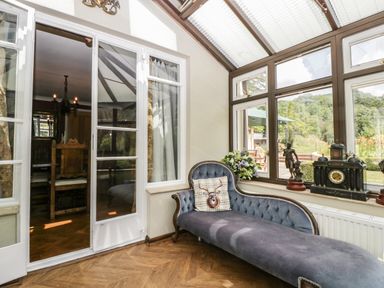 A sitting area with a chaise lounge near large windows and a door leading to a dining room at Valley House in Devizes