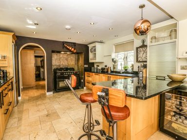 A kitchen with a black countertop island and two brown bar stools at Valley House in Devizes
