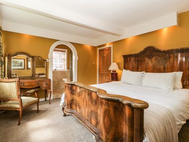 A bedroom with a wooden bed frame a desk with a mirror and a chair at Valley House in Devizes