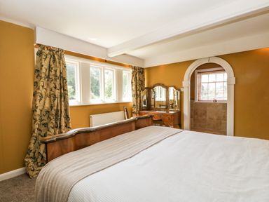 A bedroom with a wooden bed and a dressing table next to a window at Valley House in Devizes