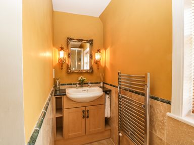 A bathroom with a sink cabinet mirror two wall lamps and a towel radiator at Valley House in Devizes