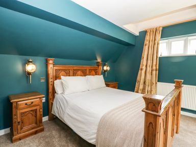 A bedroom with a wooden bed and matching bedside tables under blue walls at Valley House in Devizes