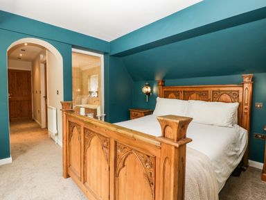 A bedroom with a carved wooden bed and blue walls at Valley House in Devizes