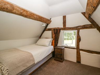 A small bedroom with a single bed a window and exposed wooden beams at Valley House in Devizes