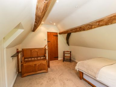 A bedroom with a wooden bench a small wooden chair and a single bed at Valley House in Devizes