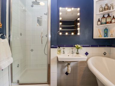 A bathroom with a shower enclosure sink with mirror and bathtub at Valley House in Devizes
