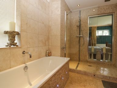 A bathroom with a bathtub and a walk-in shower with a glass door at Valley House in Devizes