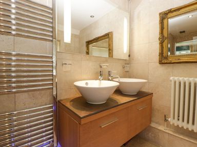 A bathroom with two round white sinks on a wooden counter and a large mirror above at Valley House in Devizes