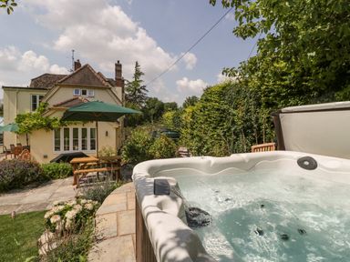 A garden with a hot tub and outdoor seating with green umbrellas at Valley House in Devizes