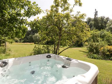 A hot tub with water flowing in a garden with trees and grass at Valley House in Devizes