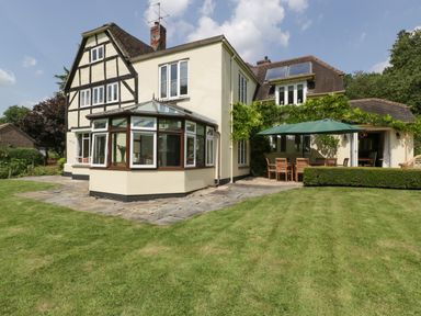 A house with a conservatory patio furniture and green lawn at Valley House in Devizes