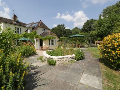 A garden with stone paths and seating areas outside a house at Valley House in Devizes