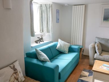 A living room with two sofas a wooden coffee table and decorative items on a window sill at Furneaux Hatch in Churchstow