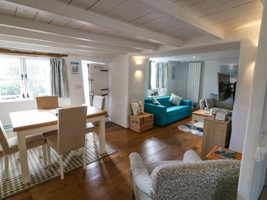 A dining area with table and chairs next to a living area with sofas and a television at Furneaux Hatch in Churchstow