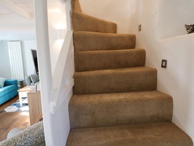 A carpeted staircase next to a living room with a blue sofa at Furneaux Hatch in Churchstow