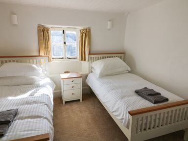A bedroom with two single beds and a nightstand between at Furneaux Hatch in Churchstow