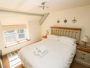 A bedroom with a bed and bedside tables with lamps at Oysterbank Cottage in Llangwm Pembrokeshire