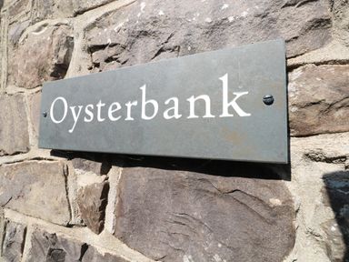 A metal sign with the word Oysterbank mounted on a stone wall at Oysterbank Cottage in Llangwm Pembrokeshire