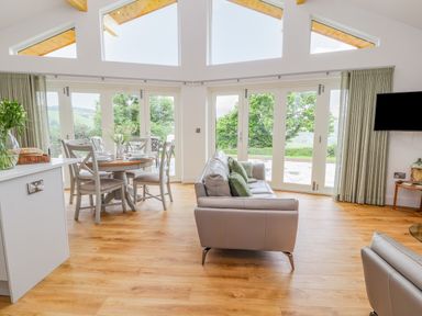 A living room and dining area with large windows overlooking greenery at Pen Bryn in Cyffylliog near Ruthin