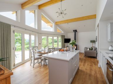 A kitchen and dining area with an island countertop and dining table near large windows at Pen Bryn in Cyffylliog near Ruthin