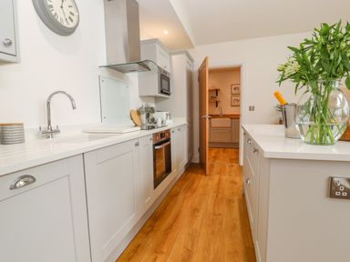 A kitchen with white cabinets wood flooring a sink oven and a vase of flowers on the counter at Pen Bryn in Cyffylliog near Ruthin