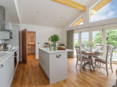 A kitchen and dining area with wooden floors and a round dining table set for four at Pen Bryn in Cyffylliog near Ruthin