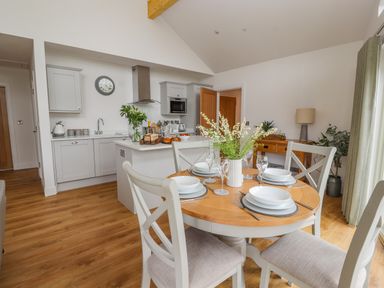 A kitchen and dining area with a round table set for four and a kitchen island with flowers at Pen Bryn in Cyffylliog near Ruthin