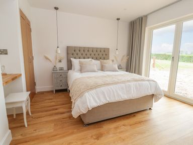 A bedroom with a bed and bedside tables next to a large window at Pen Bryn in Cyffylliog near Ruthin