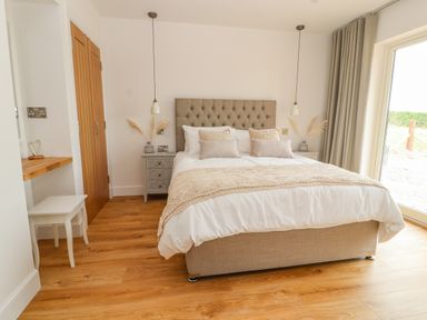 A bedroom with a double bed bedside tables and wooden flooring at Pen Bryn in Cyffylliog near Ruthin