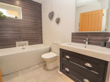 A bathroom with a bathtub toilet sink cabinet and mirror at Pen Bryn in Cyffylliog near Ruthin
